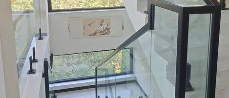 Eine moderne Treppe mit Glasgeländern und Blick auf Grünanlagen.