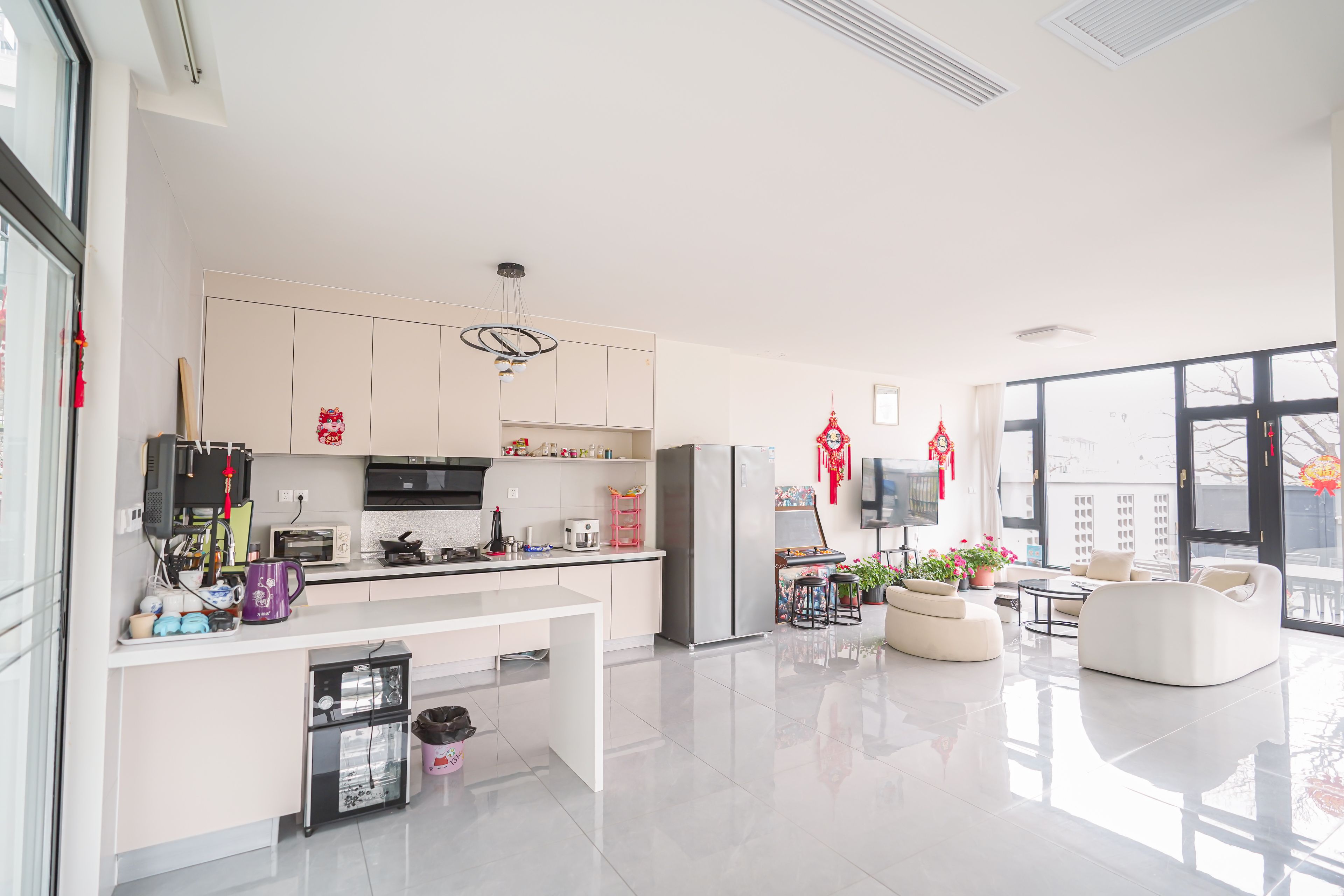 A modern kitchen with a central island, a dining area with a sofa, and a large window providing a view of the outside.
