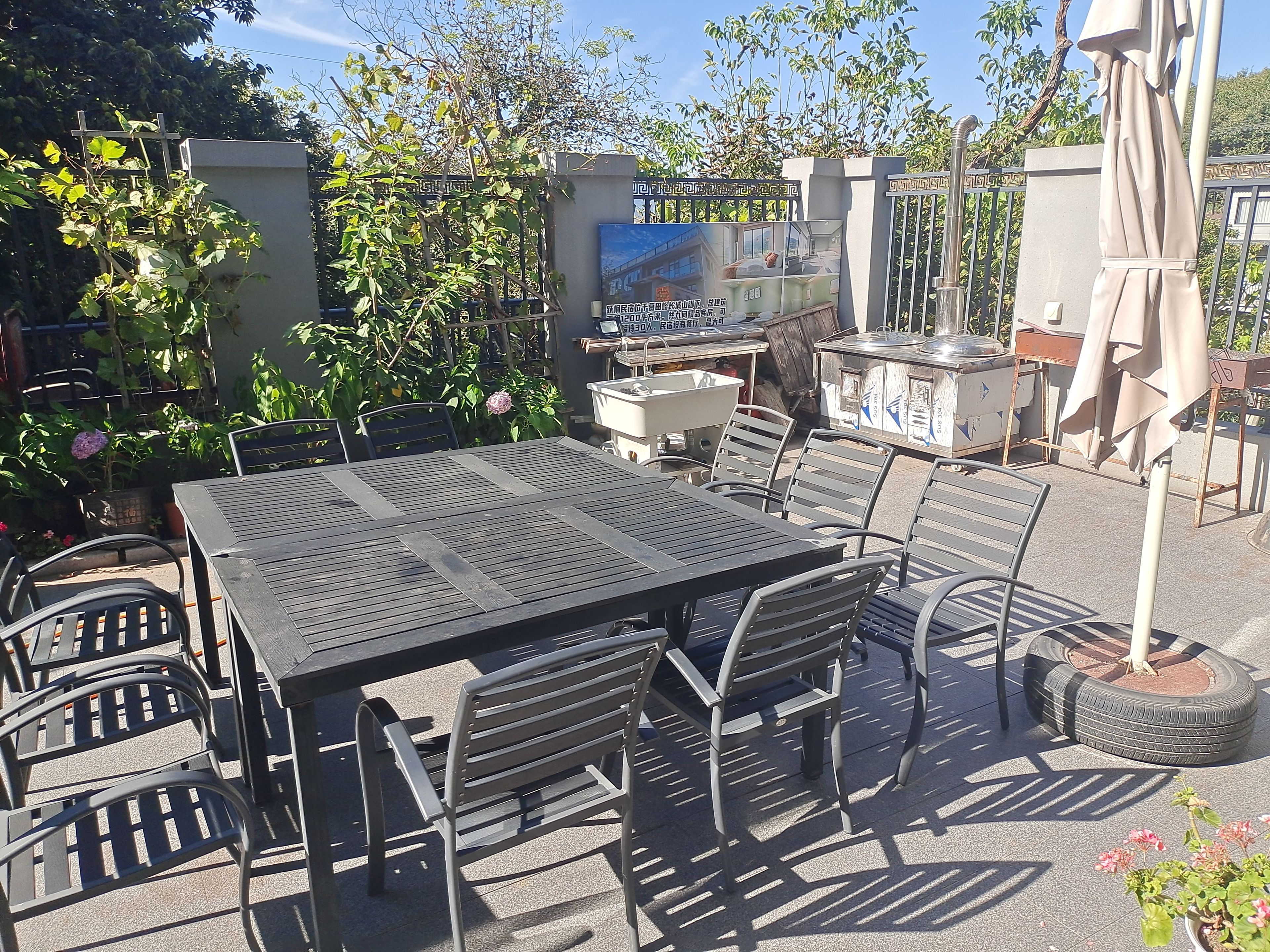An outdoor patio with a table and chairs, surrounded by greenery and a decorative fence.