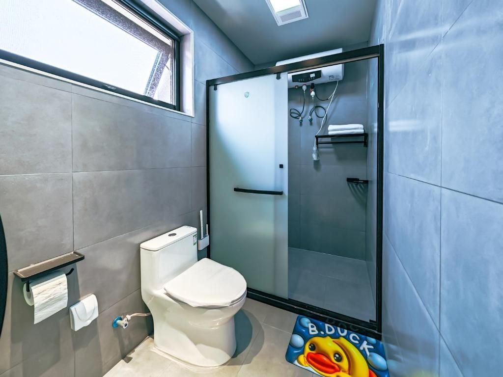 Un baño con inodoro, ducha y puerta de vidrio.