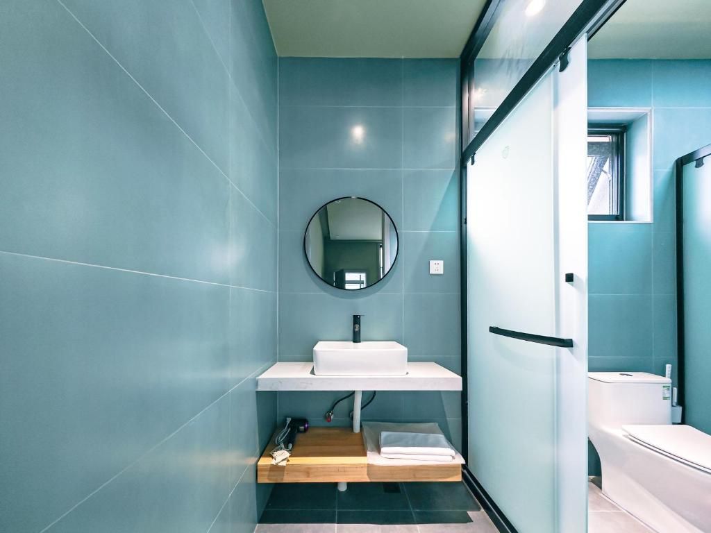 Een moderne badkamer met een wit wastafelmeubel, een ronde spiegel en een toilet.