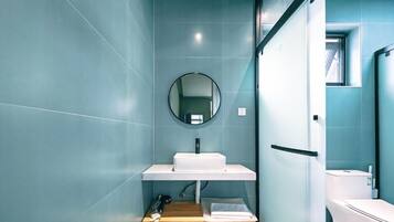 Een moderne badkamer met een wit wastafelmeubel, een ronde spiegel en een toilet.