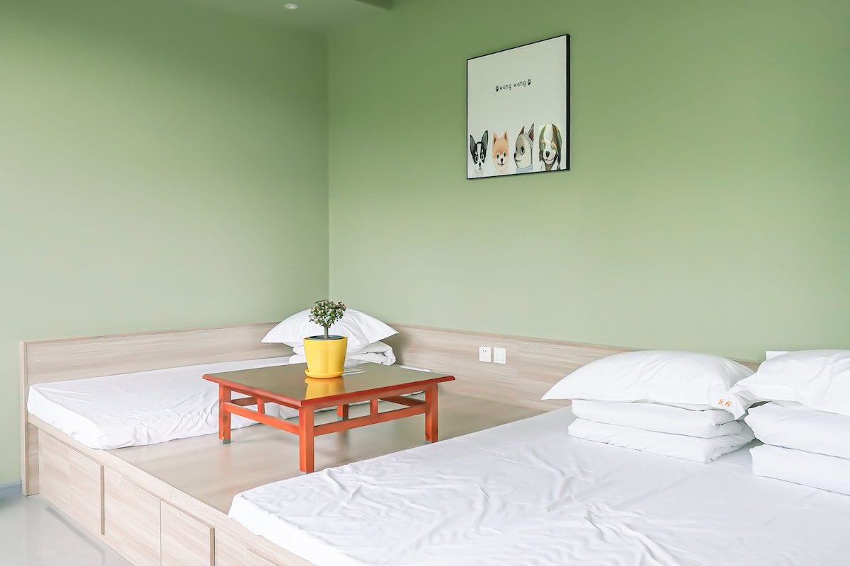 Una habitación con una cama, una mesita con una planta y un cuadro en la pared.
