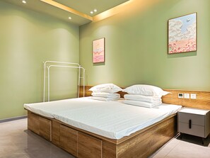 Una cama bien hecha con sábanas blancas, un cabecero de madera y una mesita de noche con un cajón.