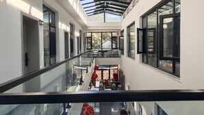 Un interior moderno con barandilla de vidrio, un entrepiso y vistas al exterior.