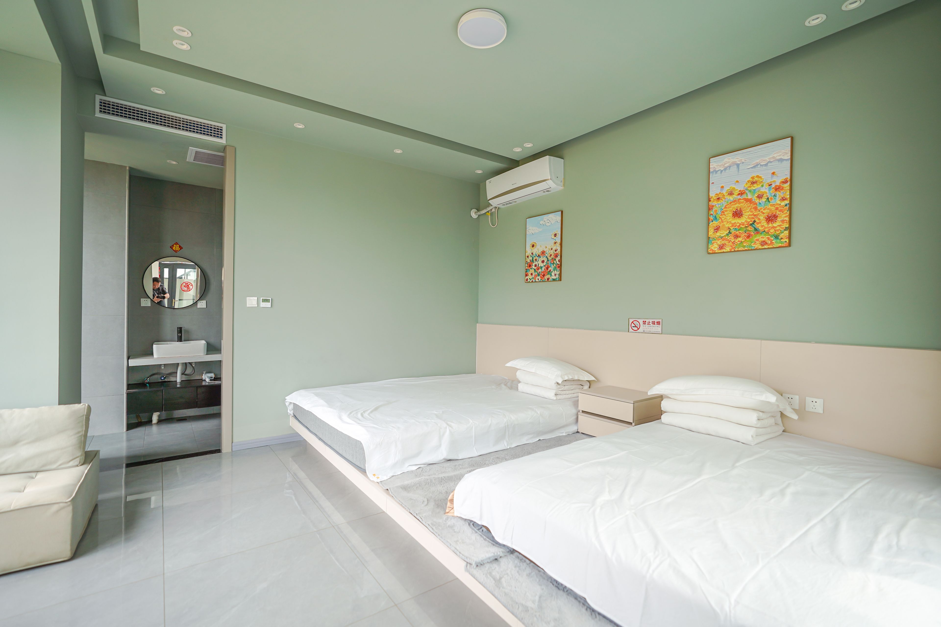 A hotel room with two beds, a bathroom, and a small sitting area.