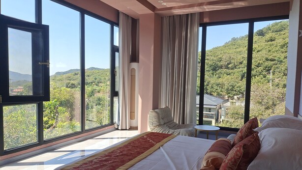Un dormitorio con una cama grande, una silla, una mesita y un televisor.