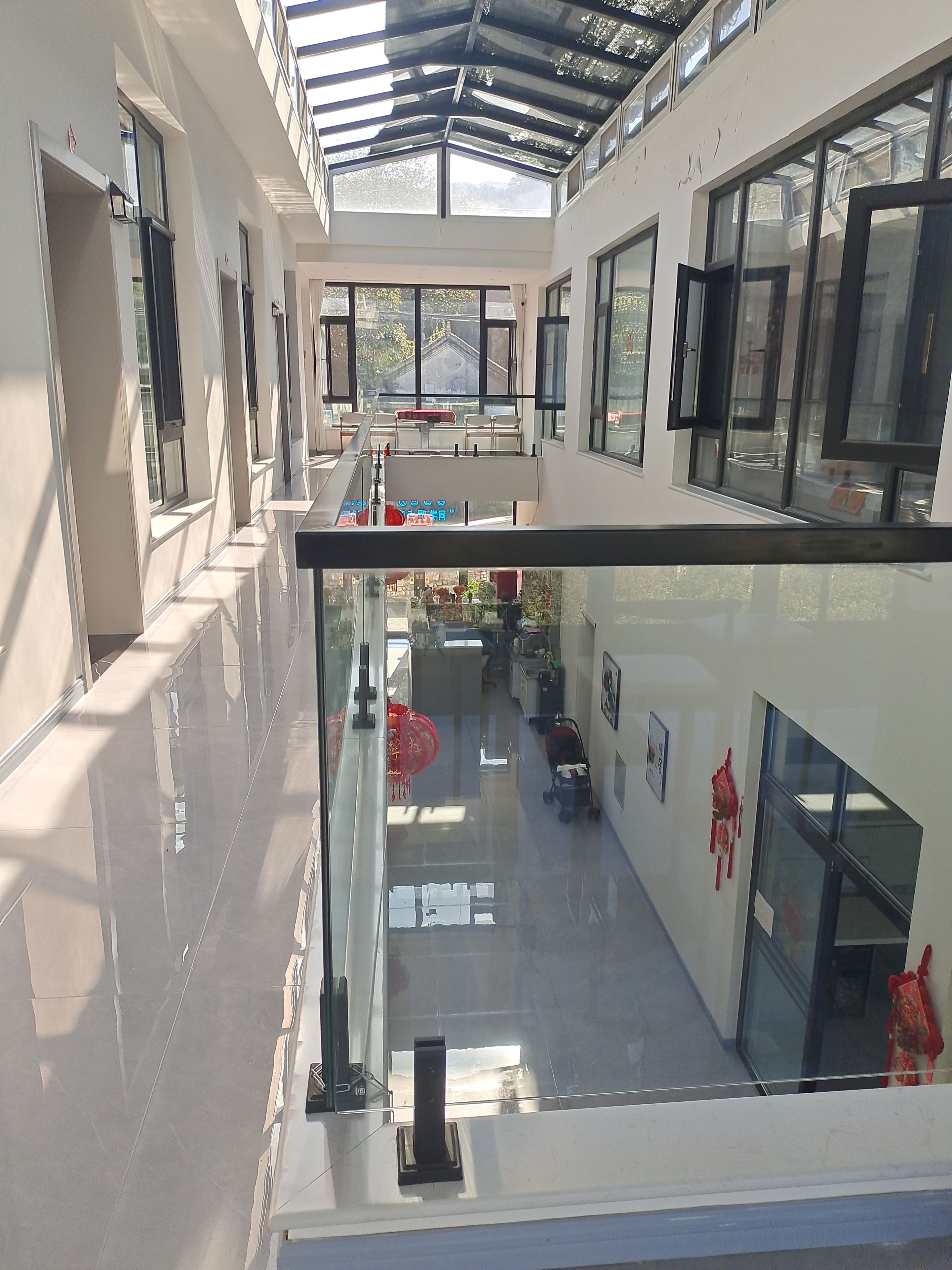 Un interior de varios niveles con barandillas de vidrio, una escalera y vistas al exterior.