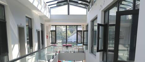 Interior de varios niveles con barandillas de vidrio, una escalera central y vistas al exterior.