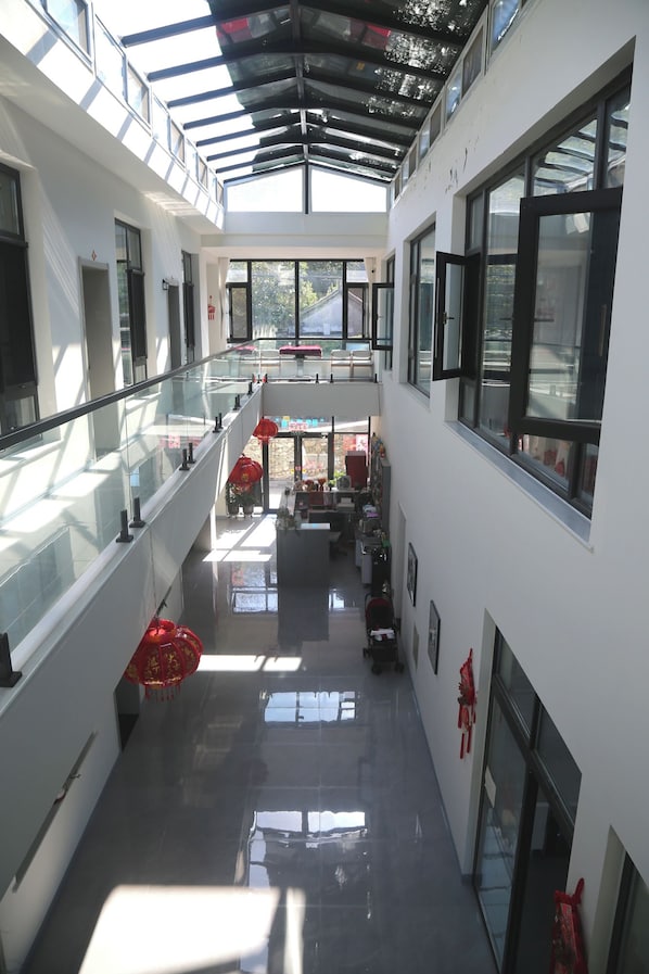 A multi-level interior with glass railings, a central staircase, and a view of the outside.
