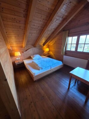 Ein Schlafzimmer einer Holzhütte mit Bett, Nachttisch und Fenster.