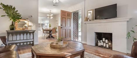 A living room with a fireplace, a television, and a dining area.