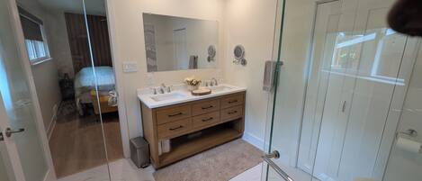 A modern bathroom with a glass shower enclosure, a wooden vanity, and a large mirror.
