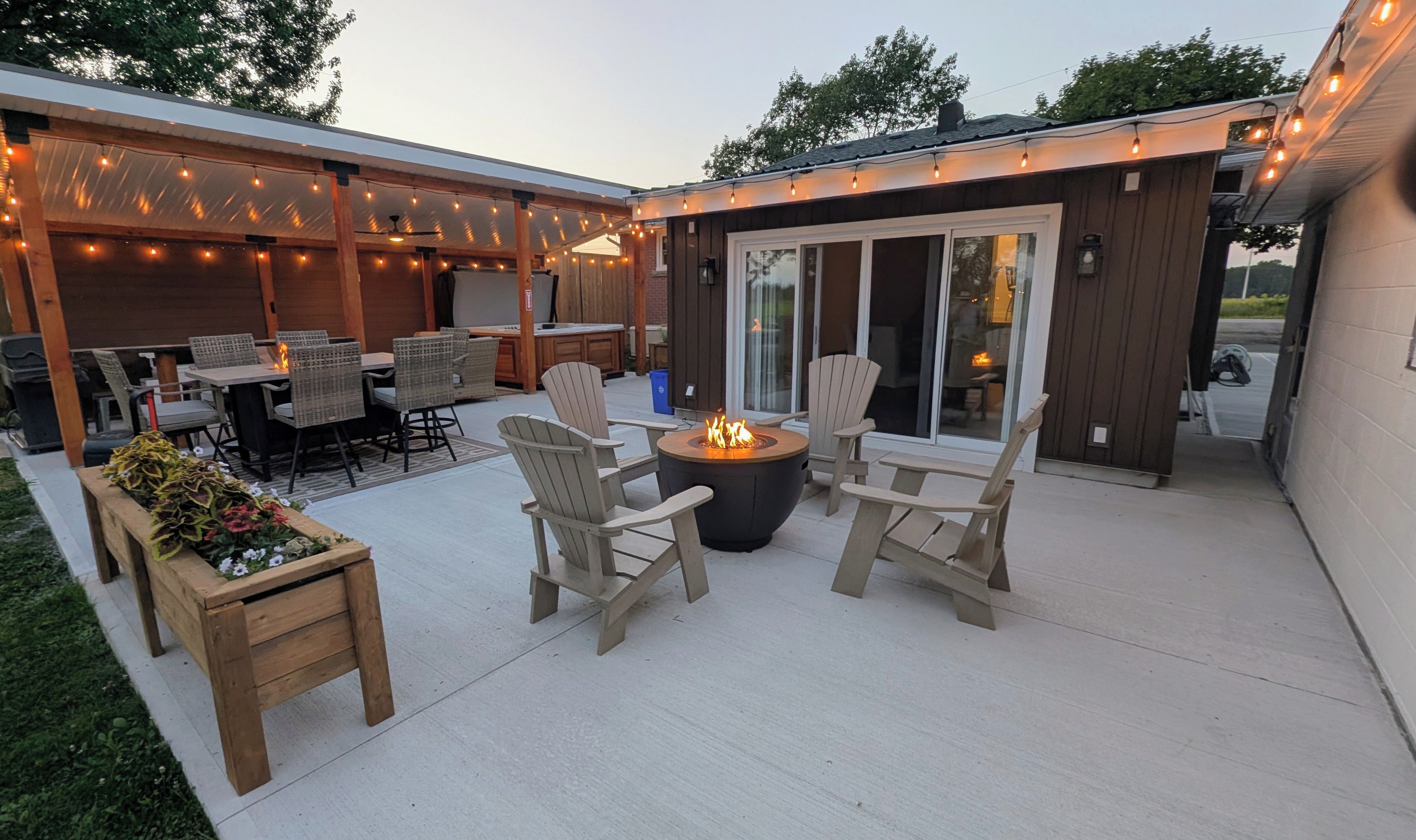 Eine Außenpatio mit Feuerstelle, Sitzgelegenheit und Lichterketten.