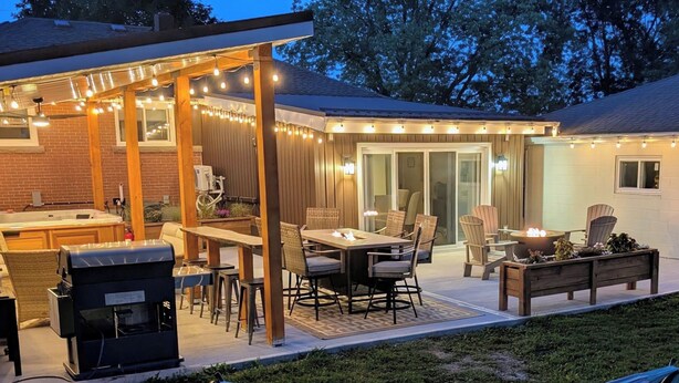 Un patio exterior con mesa y sillas, una parrilla y un brasero.