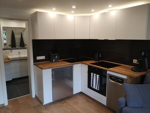 Una cocina moderna con armarios blancos, salpicadero negro y encimeras de madera.