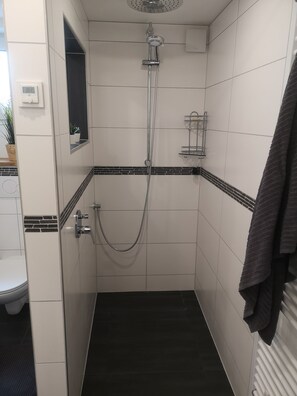Un baño pequeño y moderno con ducha, inodoro y lavamanos.