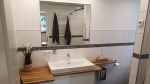Un baño moderno con un lavamanos rectangular, un espejo y una planta en maceta.