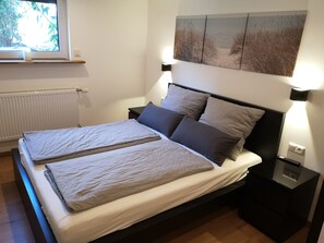 A double bed with two pillows, a bedside table with a lamp, and a wall-mounted artwork above the bed. - Cozy in Bensberg – Cologne Trade Fair & Mediterana (Bergisch Gladbach)