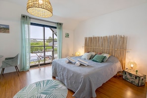 A bedroom with a bed, a chair, a window, and a view of the outdoors.