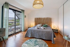 A bedroom with a large bed, a window with a view, a chair, and a round table. - Bed and Breakfast 'Chambre Bambou' with Shared Terrace, Balcony and Wi-Fi (Caen)