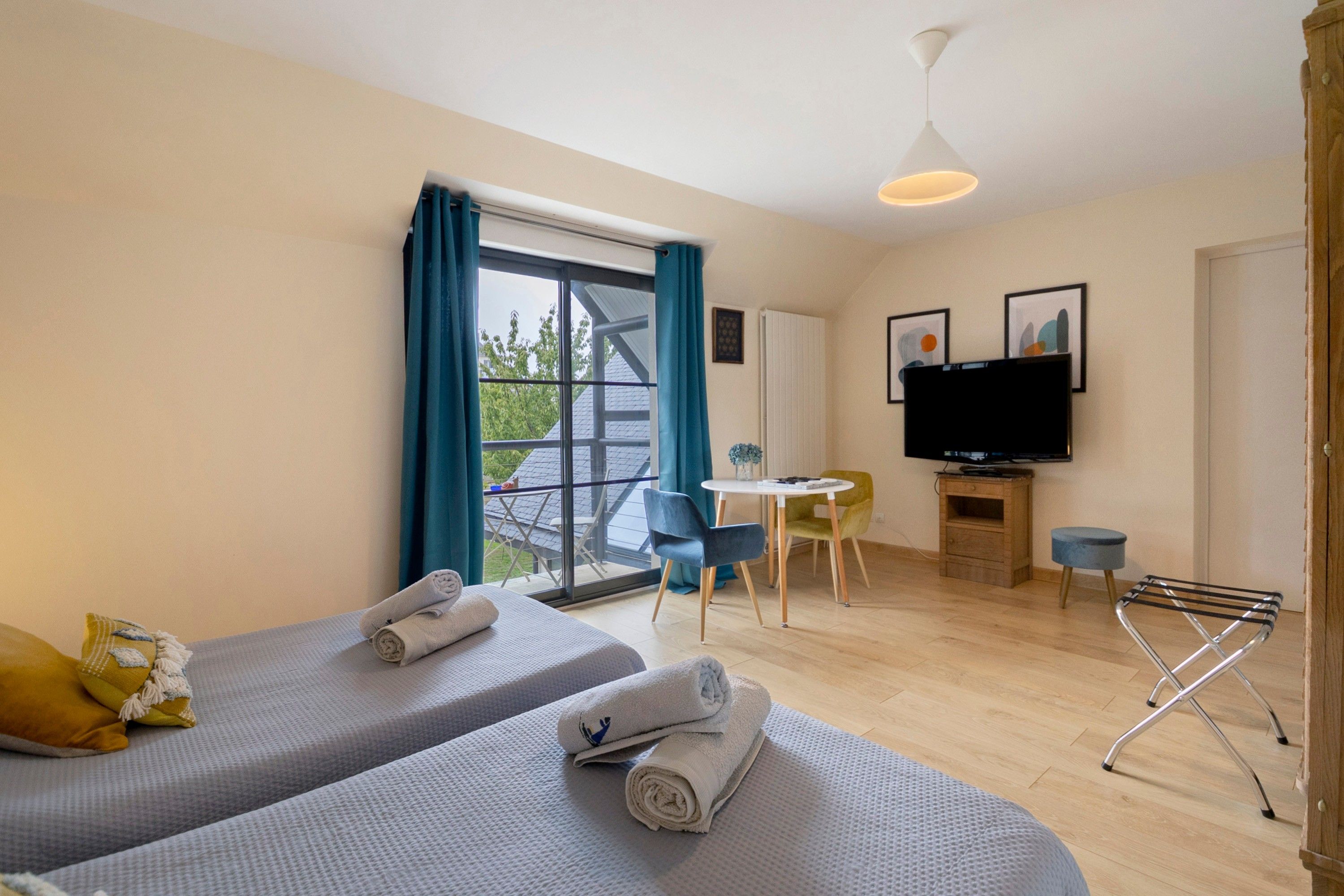 A hotel room with two beds, a television, a small table, and a chair.