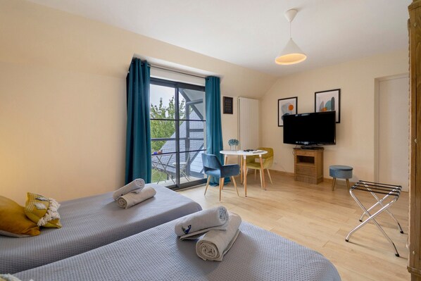 A hotel room with two beds, a television, a small table, and a chair. - Bed and Breakfast 'Chambre Vue Sur Jardin' with Shared Terrace, Balcony and Wi-Fi (Caen)