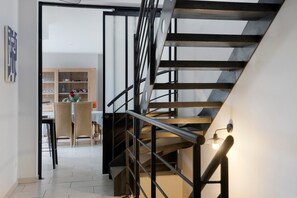 Un interior moderno con una escalera, un comedor y una estantería.