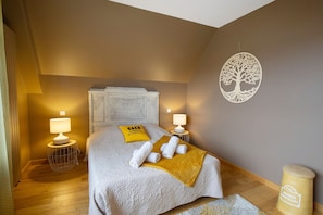 A hotel room with a bed, two bedside lamps, a decorative wall piece, and a small table with a lamp. - Bed and Breakfast 'Chambre Deuxième Étage' with Shared Terrace, Balcony and Wi-Fi (Caen)