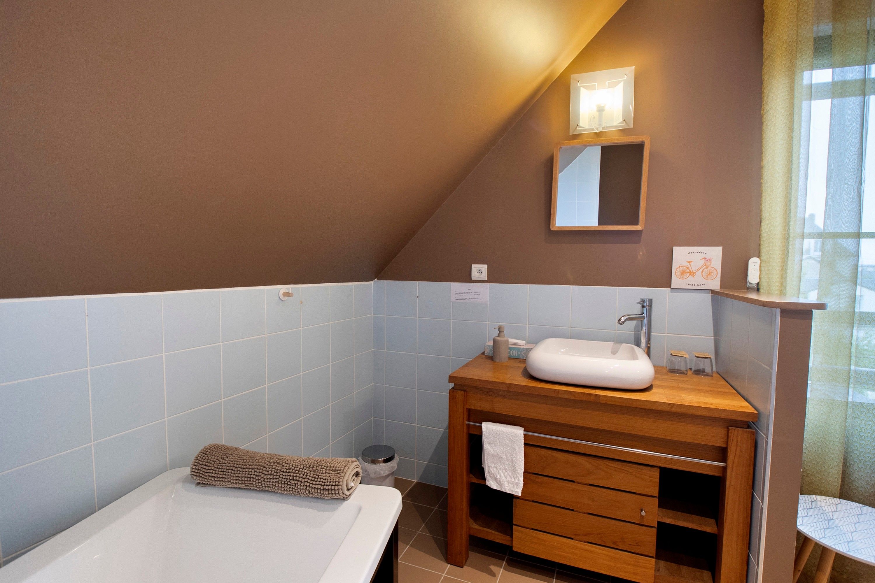 Een badkamer met een badkuip, een houten wastafelmeubel met een wastafel en een spiegel erboven.