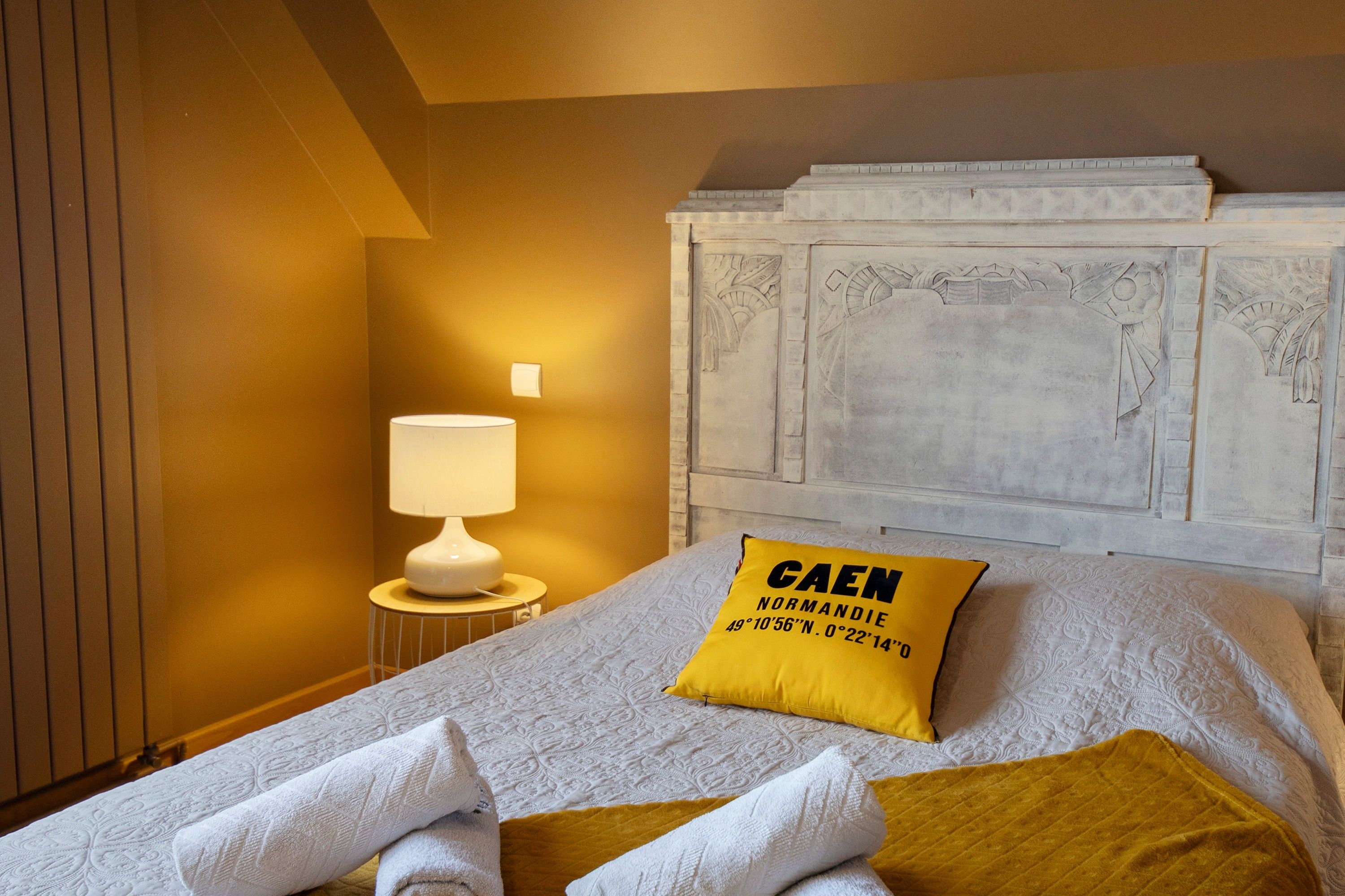 Une chambre d’hôtel comprenant un lit, une table de chevet, une lampe et une tête de lit décorative.