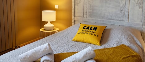 A hotel room with a bed, a nightstand, a lamp, and a decorative headboard.