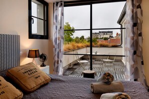 A bedroom with a large window, a bed with a patterned bedspread, a lamp, and a view of the outside. - Bed and Breakfast 'Chambre Black and White' with Shared Terrace, Balcony and Wi-Fi (Caen)