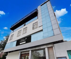 A modern building with a glass facade, a prominent black sign with white lettering, and a clear blue sky in the background. - Classic Hotel Metro View (Jaipur)