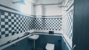 Un baño con piso de baldosas a cuadros, un lavamanos, un inodoro y un espejo.