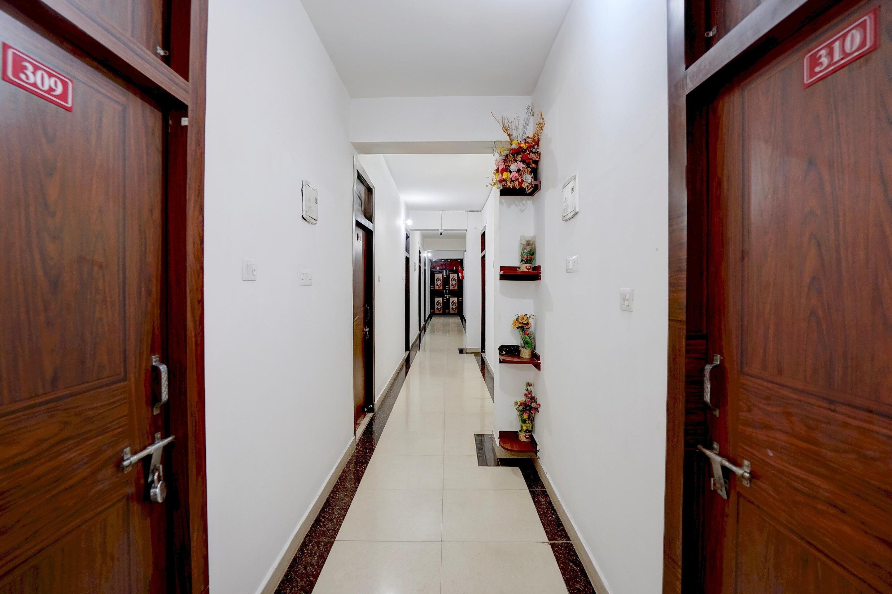 A hotel corridor with wooden doors, numbered 309 and 310, and a tiled floor.