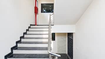 A modern staircase with a metal handrail, leading to a landing with a small window.