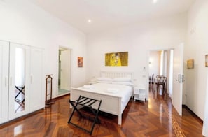 A bedroom with a bed, a chair, and a painting on the wall. - Marina Rooms (Napoli)
