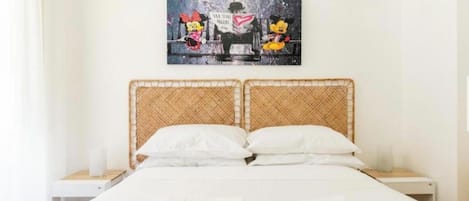 A hotel room with a bed, two nightstands, a wall-mounted artwork, and a window with curtains.