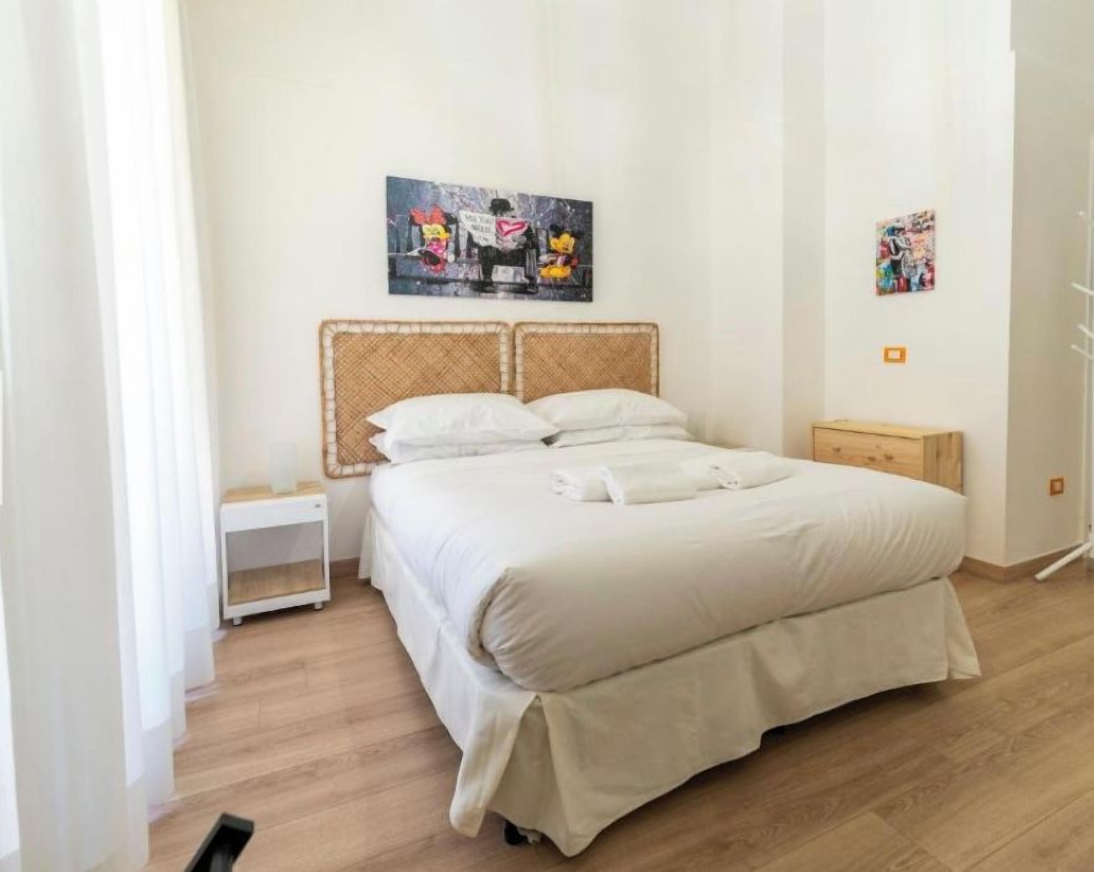 Ein Schlafzimmer mit einem Bett, einem Nachttisch und einem Wandbild.