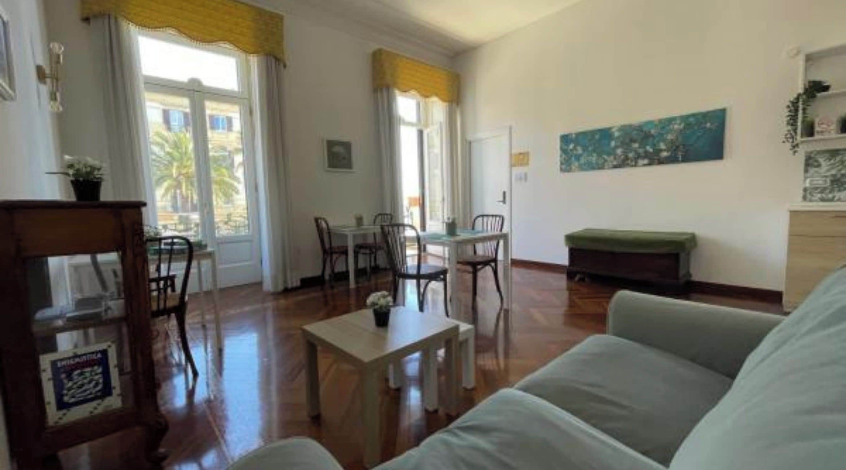 Un soggiorno con un divano, un tavolo da pranzo con sedie e un quadro appeso al muro.