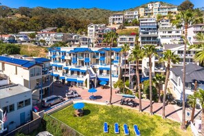 Ein Küstenhotel mit mehrstöckigen Gebäuden, einem Poolbereich mit Liegestühlen und Palmen.