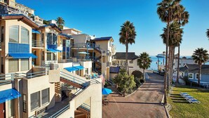 Un hôtel en bord de mer doté de nombreux balcons, de palmiers et offrant une vue dégagée sur l’océan.