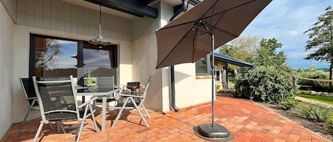 An outdoor patio with a table and chairs, a large umbrella, and a brick floor.