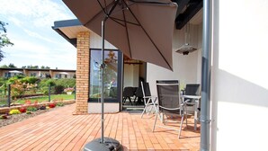 Un patio al aire libre con piso de ladrillo, una mesa y sillas, y un paraguas grande.
