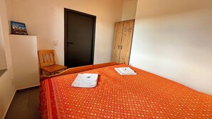 Una habitación pequeña con una cama, una silla, un armario y una puerta.