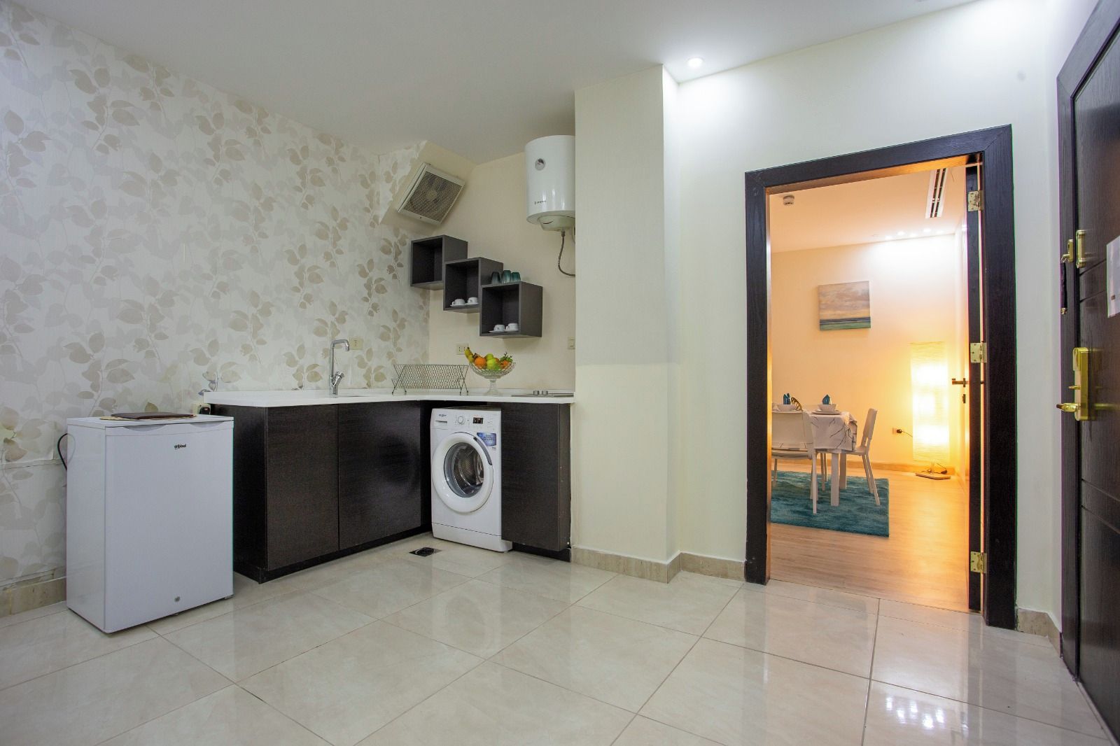 A compact kitchen with a washing machine, a small fridge, and a sink.