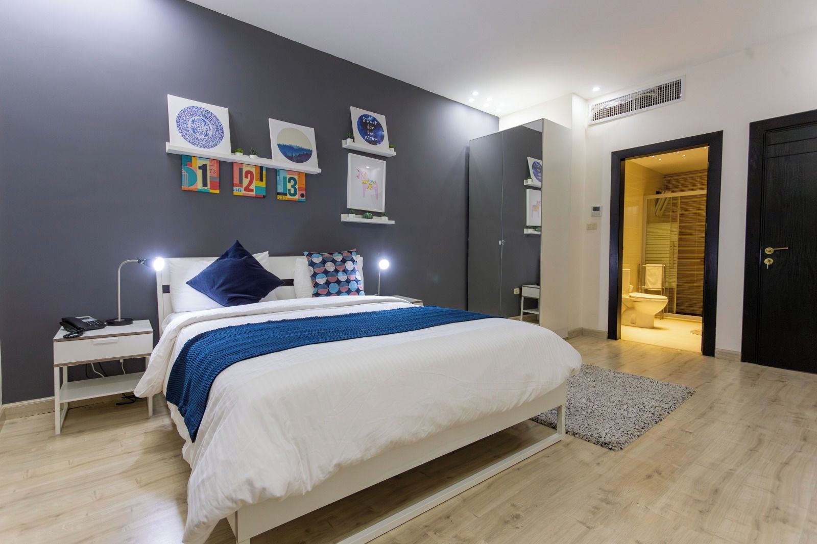 A modern bedroom with a bed, bedside table, and wall art.