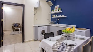 A compact living space with a dining area, a washing machine, and a small kitchen. - ALBASEM Hotel Apartments (Amman)