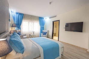 Een hotelkamer met een bed, een bureau, een stoel, een televisie en een badkamers deur.